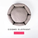 A top-down view of a dusty elephant grey luxury donut dog bed with high-wall padded sides and a round mattress inside, on a white background with the text 'COSMO ELEPHANT' and a pink 'Core Collection' label below.