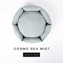 A top-down view of a pale sea-mist grey-green luxury donut dog bed with high-wall padded sides and a round mattress inside, on a white background with the text 'COSMO SEA MIST' and a black 'Styled To Order' label below.