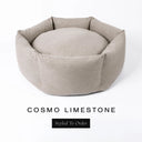 A luxury donut dog bed in pale limestone grey Cosmo fabric, suitable for all breeds of dogs, with cosy high-wall sides and a deep-filled luxury mattress inside, on a white background with the text 'COSMO LIMESTONE' and 'Styled To Order' below.