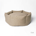 A luxury dog donut bed by Charley Chau with high-sides in a beige upholstery fabric on a white backdrop