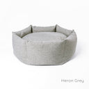A luxury dog donut bed by Charley Chau with high-sides in a grey upholstery fabric on a white backdrop.
