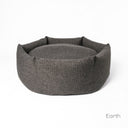 A luxury dog donut bed by Charley Chau with high-sides in a dark brown/black upholstery fabric on a white backdrop.