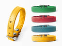 A set of five leather puppy collars in various colors (yellow, green, red, teal, and mustard yellow) on a clean white background, with one yellow collar shown in a close-up profile view on the left.