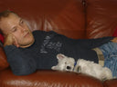 2005: Geoff Thompson hanging out on a brown leather couch with a small white Westie puppy dog. 