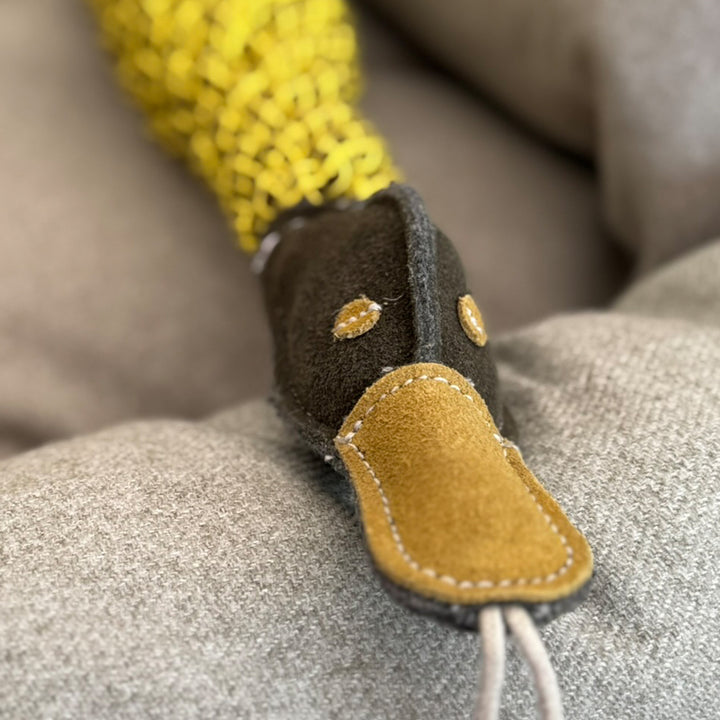 Close up of a Dog Toy made from yellow jute rope with a duck-shaped head of green suede.