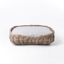A luxury wicker dog bed made with a natural rattan dog basket and pale grey mattress on a white background.