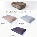 A greywash rattan dog basket shown with three different colour luxury dog bed mattresses.