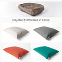 A greywash rattan dog basket shown with four different colour luxury dog bed mattresses.