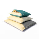 A stack of three different size Dog Snuggle Beds in jade green, pale beige and grey, with a dog sleeping cosy in the snuggle bed on the stop of the stack on a white backdrop.