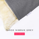 A close up detail of the corner of a Charley Chau Dog Snuggle Bed with grey outer cover in upholstery-quality woven-wool texture fabric Faroe, and plush cream faux-fur lining with a woven brand label showing the Charley Chau logo on a white backdrop.