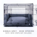 A wire dog dog crate with a luxury dog crate mattress and crate bed bumper set in dark grey on a white backdrop.