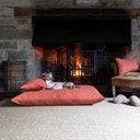 A dog lying on a luxury dog bed mattress with a small mini bolster pad cushion on the dog bed mattress in front of a fireplace.