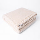 Folded beige colour luxury Sherpa Fleece Dog Blanket showing a designer label for Charley Chau ona white backdrop.