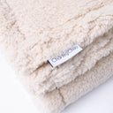 Close up detail of the Charley chau designer brand label on a luxury Sherpa Fleece Dog Blanket in beige. 