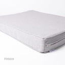 Corner detail view of a luxury orthopaedic memory foam dog bed mattress  in a very pale grey upgolstery fabric with the designer label for Charley Chau showing on a white backdrop. 