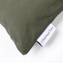 Close up of the corner of a dark green water-resistant, tough dog bed, showing a white Cahrley Chau woven brand label, on a white backdrop.