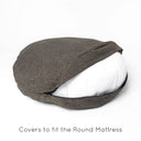 A deep-filled round dog bed mattress in a woven upholstery fabric in dark brown / black with the bed cover zip unzipped to show a white deep-filled mattress on a white backdrop.