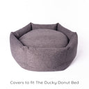 A luxury dog donut bed in a woven upholstery fabric in dark brown / black with high bed sides and a deep-filled luxury mattress on a white backdrop.