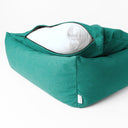 A jade green luxury box bed style luxury dog bed with high sides and the dog bed mattress lifted up slightly with the zip unzipped revewaling the internal mattress pad on a white backdrop.