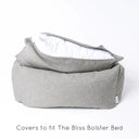 Luxury box-style dog bed, Charley Chau's luxury Bliss Bolster dog Bed in a grey colour with the mattress lifted up slightly and the mattress cover unzipped to show the internal mattress insert on a white backdrop.
