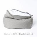 Luxury box-style dog bed, Charley Chau's luxury Bliss Bolster dog Bed in a grey colour with the mattress lifted up slightly and the mattress cover unzipped to show the internal mattress insert on a white backdrop.