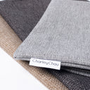 Close up of three spare dog bed covers in a heavy duty upholsyer-quality fabric in dark brown, grey and beige, with a Charley Chau brand label.