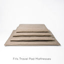 A stack of four slimline luxury travel pads for dogs in four different sizes, in a beige upholstery quality fabric by designers Charley Chau with text "Covers to fit Travel Pads" on a white backdrop.