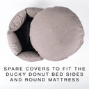 A top-down view of a premium machine washable, round donut-style dog bed in a grey taupe fabric with the round mattress lifted out of the bed sides. Text at the bottom reads: 'SPARE COVERS TO FIT THE DUCKY DONUT BED SIDES AND ROUND MATTRESS'.
