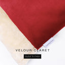 A close up detail of the corner of a Charley Chau Dog Snuggle Bed and dog Burrow Bag Dog Bed Cover with red outer cover in upholstery-quality Velour and plush cream faux-fur lining with a woven brand label showing the Charley Chau logo on a white backdrop.