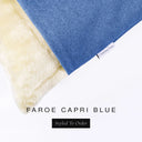 A close up detail of the corner of a Charley Chau Dog Snuggle Bed and dog Burrow Bag Dog Bed Cover with bright blue outer cover in woven wool texture upholstery-quality Faroe and plush cream faux-fur lining with a woven brand label showing the Charley Chau logo on a white backdrop.