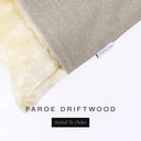 A close up detail of the corner of a Charley Chau Dog Snuggle Bed and dog Burrow Bag Dog Bed Cover with pale taupe grey outer cover in woven wool texture upholstery-quality Faroe and plush cream faux-fur lining with a woven brand label showing the Charley Chau logo on a white backdrop.
