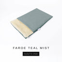 A folded spare dog bed cover to fit Charley Chau Snuggle Dog Beds and Dog Burrow Bags with soft teal grey outer cover in woven wool texture upholstery-quality Faroe and plush cream faux-fur lining on a white backdrop.