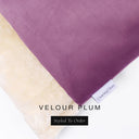 A close up detail of the corner of a Charley Chau Dog Snuggle Bed and dog Burrow Bag Dog Bed Cover with deep plum purple outer cover in upholstery-quality Velour and plush cream faux-fur lining with a woven brand label showing the Charley Chau logo on a white backdrop.