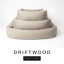 Three sizes of the Bliss Bolster Dog Bed in a warm sandy taupe 'DRIFTWOOD' Faroe fabric nested together, showing this long lasting dog bed with sides in Small, Medium and Large; a hard-wearing bolster dog bed and high-wall dog bed for everyday comfort.