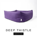 Close-up corner view of a rich deep purple Bliss Bolster Dog Bed in 'DEEP THISTLE' Faroe fabric with a black 'Styled To Order' label, showing the tall walls of this long lasting dog bed with sides; a durable bolster dog bed and high-wall dog bed built to last.