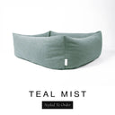 Close-up corner view of a muted sage teal Bliss Bolster Dog Bed in 'TEAL MIST' Faroe fabric with a black 'Styled To Order' label, showing the tall walls of this long lasting dog bed with sides; a durable bolster dog bed and high-wall dog bed built to last.