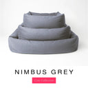 Three sizes of the Bliss Bolster Dog Bed in a cool blue-grey 'NIMBUS GREY' Faroe fabric nested together, showing this long lasting dog bed with sides in Small, Medium and Large; a hard-wearing bolster dog bed and high-wall dog bed for everyday comfort.