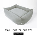 A classic mid grey Bliss Bolster Dog Bed in 'TAILOR'S GREY' Faroe fabric shown from an angle on a white background, highlighting the tall sides of this long lasting dog bed with sides; a stylish bolster dog bed and high-wall dog bed for dogs of all sizes.
