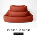 Three sizes of the Bliss Bolster Dog Bed in a warm terracotta orange-red 'FIRED BRICK' Faroe fabric nested together, showing this long lasting dog bed with sides in Small, Medium and Large; a hard-wearing bolster dog bed and high-wall dog bed for everyday comfort.