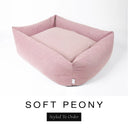 A soft blush pink Bliss Bolster Dog Bed in 'SOFT PEONY' Faroe fabric shown from an angle on a white background, highlighting the tall sides of this long lasting dog bed with sides; a stylish bolster dog bed and high-wall dog bed for dogs of all sizes.