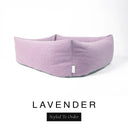 Close-up corner view of a soft dusky pink-lilac Bliss Bolster Dog Bed in 'LAVENDER' Faroe fabric with a black 'Styled To Order' label, showing the tall walls of this long lasting dog bed with sides; a durable bolster dog bed and high-wall dog bed built to last.