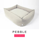A warm stone grey Bliss Bolster Dog Bed in 'PEBBLE' Faroe fabric shown from an angle on a white background, highlighting the tall sides of this long lasting dog bed with sides; a stylish bolster dog bed and high-wall dog bed for dogs of all sizes.