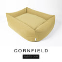A warm golden mustard Bliss Bolster Dog Bed in 'CORNFIELD' Faroe fabric shown from an angle on a white background, highlighting the tall sides of this long lasting dog bed with sides; a stylish bolster dog bed and high-wall dog bed for dogs of all sizes.