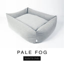 A soft pale grey Bliss Bolster Dog Bed in 'PALE FOG' Faroe fabric shown from an angle on a white background, highlighting the tall sides of this long lasting dog bed with sides; a stylish bolster dog bed and high-wall dog bed for dogs of all sizes.
