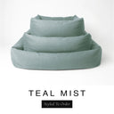 Three sizes of the Bliss Bolster Dog Bed in a muted sage teal 'TEAL MIST' Faroe fabric nested together, showing this long lasting dog bed with sides in Small, Medium and Large; a hard-wearing bolster dog bed and high-wall dog bed for everyday comfort.