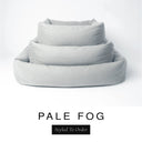 Three sizes of the Bliss Bolster Dog Bed in a soft pale grey 'PALE FOG' Faroe fabric nested together, showing this long lasting dog bed with sides in Small, Medium and Large; a hard-wearing bolster dog bed and high-wall dog bed for everyday comfort.