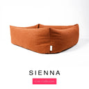 Close-up corner view of a warm burnt orange Bliss Bolster Dog Bed in 'SIENNA' Faroe fabric with a pink 'Core Collection' label, showing the tall walls of this long lasting dog bed with sides; a durable bolster dog bed and high-wall dog bed built to last.