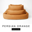 Three sizes of the Bliss Bolster Dog Bed in a warm amber orange 'PERSIAN ORANGE' Faroe fabric nested together, showing this long lasting dog bed with sides in Small, Medium and Large; a hard-wearing bolster dog bed and high-wall dog bed for everyday comfort.