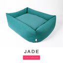 A deep teal green Bliss Bolster Dog Bed in 'JADE' Faroe fabric shown from an angle on a white background, highlighting the tall sides of this long lasting dog bed with sides; a stylish bolster dog bed and high-wall dog bed for dogs of all sizes.