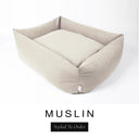 A soft warm cream Bliss Bolster Dog Bed in 'MUSLIN' Faroe fabric shown from an angle on a white background, highlighting the tall sides of this long lasting dog bed with sides; a stylish bolster dog bed and high-wall dog bed for dogs of all sizes.